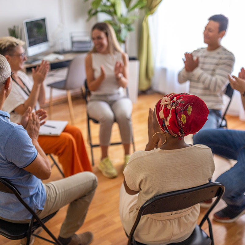 Multiracial people applauding during support group psychotherapy